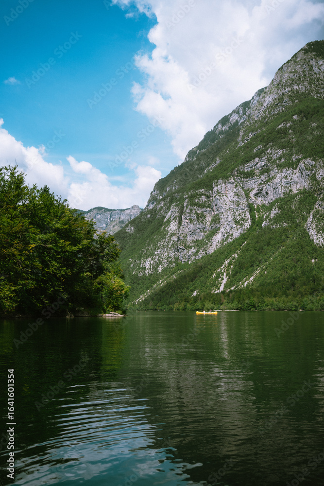 Fototapeta premium Lake with mountains, trees, and a yellow kayak.