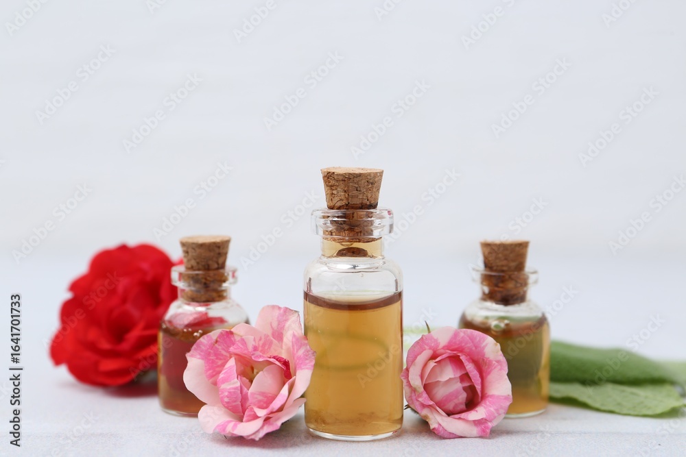 Bottles of cosmetic products, roses and sage on white table, closeup Bottles of cosmetic products, roses and sage on white table, closeup