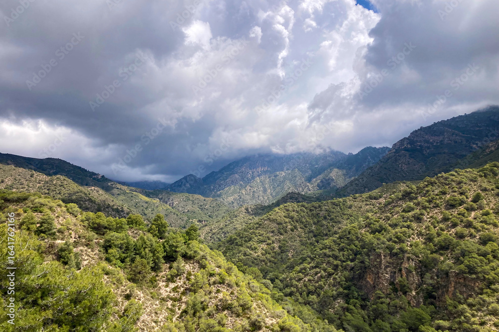 Naklejka premium Scenic view of surrounding mountains and picturesque village from a hiking trail along an old irrigation ditch in Frigiliana, Spain.