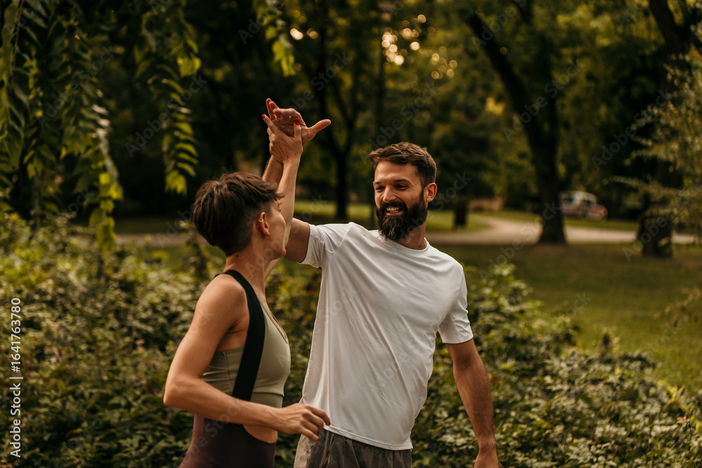 Happy couple giving high five after exercising together in park Happy couple giving high five after exercising together in park