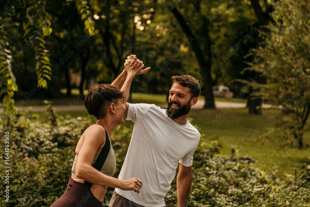 Fototapeta premium Happy couple giving high five while running in park