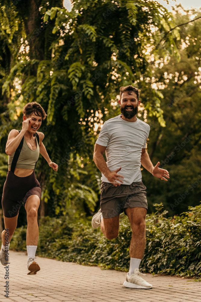 Fototapeta premium Happy couple running and smiling in city park