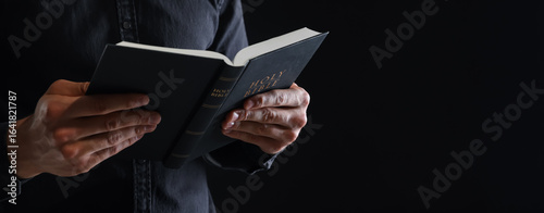 Εκτύπωση καμβά Priest with Holy Bible on black background, closeup