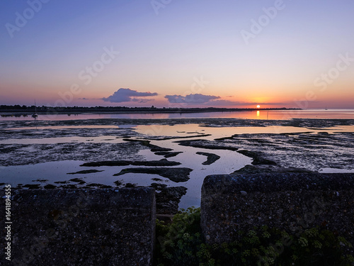 The sun and tide rise together by the Port of Loix, France