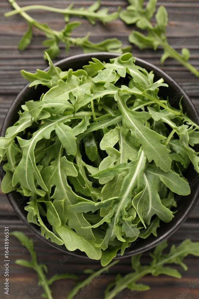 Fototapeta premium Fresh ripe green arugula leaves on dark wooden table, flat lay