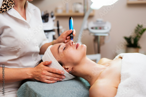 Fotografija Professional beautician using a plasma pen device, performing a non-surgical ski