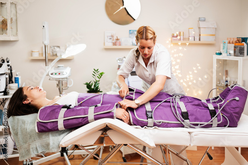 Photos Professional beautician preparing pressotherapy lymphatic massage treatment by a