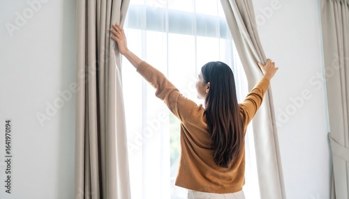Woman opening curtains, enjoying sunlight
