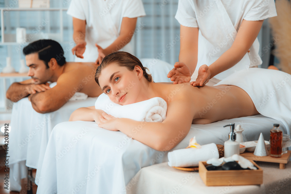 Obraz premium Caucasian couple customer enjoying relaxing anti-stress spa massage and pampering with beauty skin recreation leisure in day light ambient salon spa at luxury resort or hotel. Quiescent
