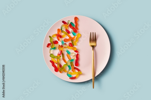 Gummy worms on plate with fork and sugar theme