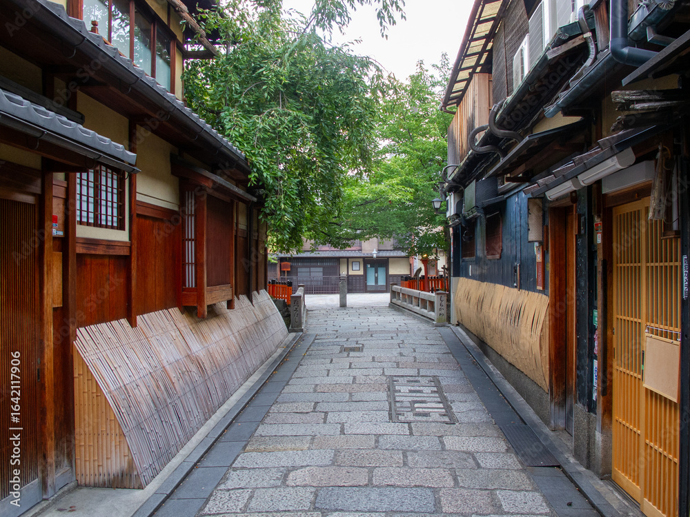 Fototapeta premium 京都の有名観光地の祇園の切通しの通りから見える京町家と祇園白川に架かる巽橋の無人の風景