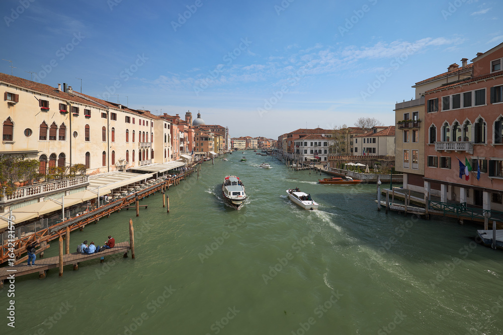 Obraz premium View of a busy canal with boats and historic buildings in Venice during a clear day