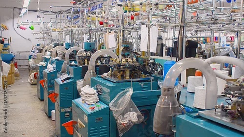 Workshop with row of blue knitting machines in textile factory, designed for production of socks