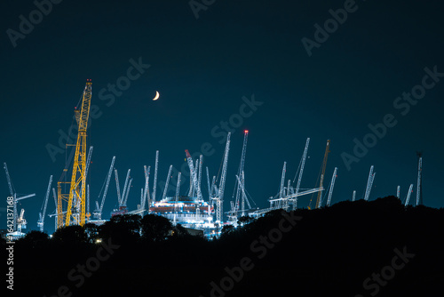 crescent moon above a nuclear power station being built at night.