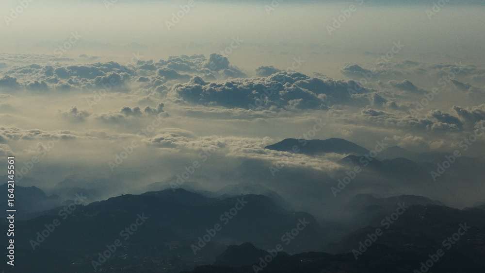 Fototapeta premium Drone view of a breathtaking mountain landscape above the clouds, showcasing rugged peaks and serene valleys in a stunning high-altitude natural scene.