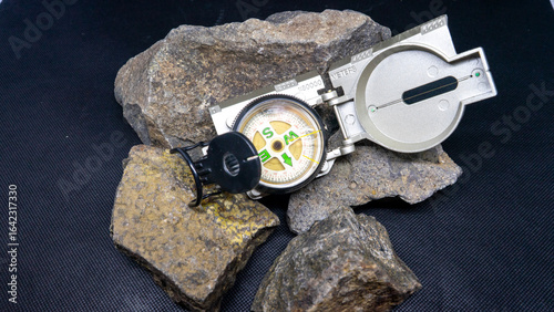 Silver Compass on Rocks Against Black Background Adventure Concept