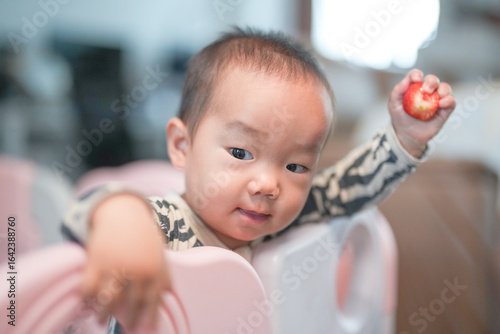 A Chinese family gathers in their living room as a one-year-old baby plays inside a child safety fence, surrounded by cozy furniture and warm light, enjoying the moment. Spring. Shanghai. China.