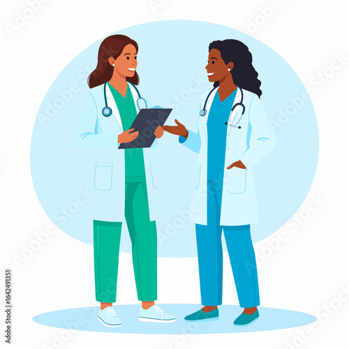 Two diverse female doctors in scrubs and lab coats smiling while discussing a medical clipboard.
