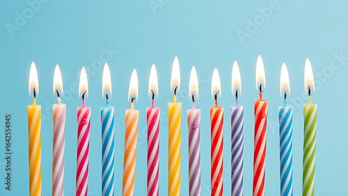 Row of colorful birthday candles with flickering flames, isolated on a soft blue background.