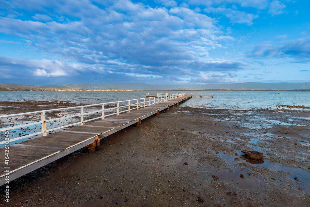 Obraz premium Photograph of an old wooden jetty in Lake Illawarra near Warrigal in the Illawarra region on the south coast of New South Wales, Australia. 
