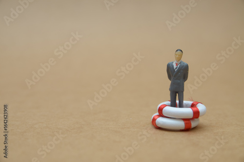 Business Stability Concept – Figurine in Life Buoy Representing Corporate Safety Net and Crisis Support