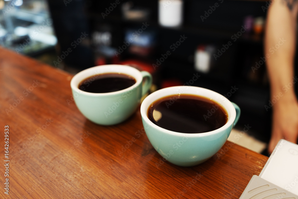 Barista carefully setting down mugs with hot coffee Barista carefully setting down mugs with hot coffee