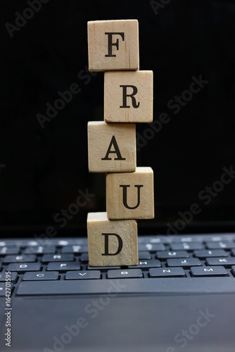 wooden block on a computer keyboard that says 'FRAUD' represents the concept of cybercrime.