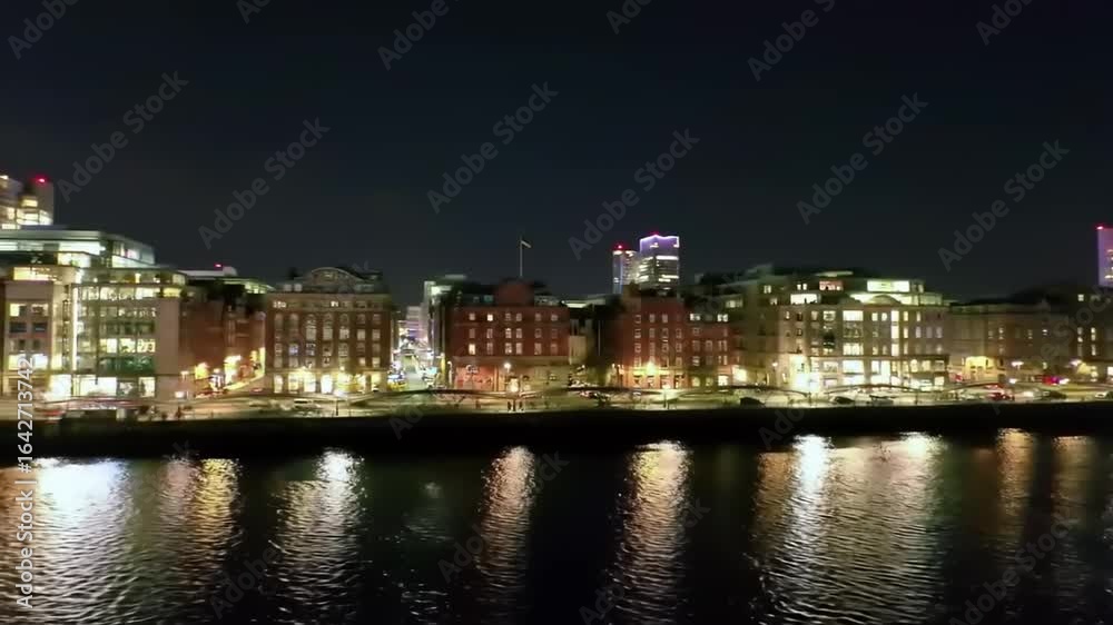 Nighttime cityscape view of illuminated buildings along a river with reflections and skyline Nighttime cityscape view of illuminated buildings along a river with reflections and skyline