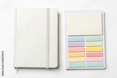 Close up view of a white notebook and colorful sticky notes on a white background.