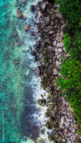 Scenic aerial perspective of ocean waves breaking on a rocky coastline.