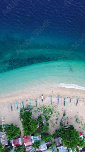 Colorful fishing boats anchored along a peaceful, pristine beach.