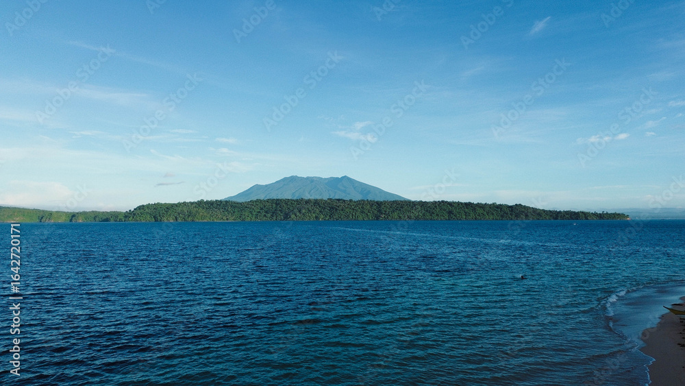 Fototapeta premium Aerial shot of serene island and dramatic volcanic mountain skyline.