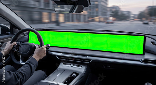 Man driving a modern car with a large green screen dashboard for mockup, view from inside the vehicle.