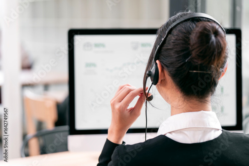 Tableau sur toile A professional customer service representative, seen from behind, wears a headse