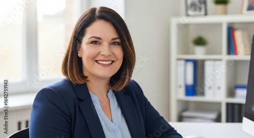 Professional caucasian businesswoman in a blue blazer smiling in a modern office setting