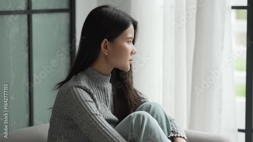 Young Asian Woman Feeling Sad and Lonely Thinking about Problems on Sofa at Home