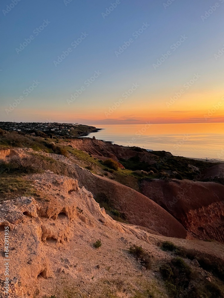 Obraz premium Golden sunset over rugged coastal cliffs, where warm light meets the calm ocean, creating a breathtaking view of nature’s beauty. South Australia.