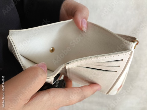 An open empty wallet in a woman's hands. The concept of poverty, lack of money, and debt.