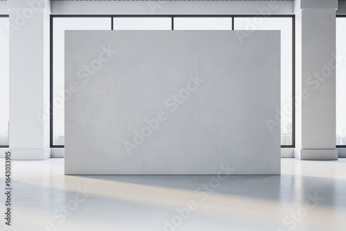 Fototapeta Naklejka Na Ścianę i Meble -  Empty grey exhibition wall in modern gallery room with large windows and city view in background, perfect for artwork or poster mockup display. 3D Rendering