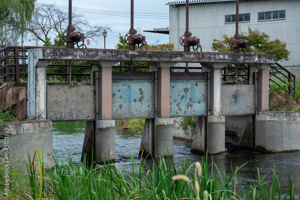 Naklejka premium 老朽化した水門と静かな川の流れ