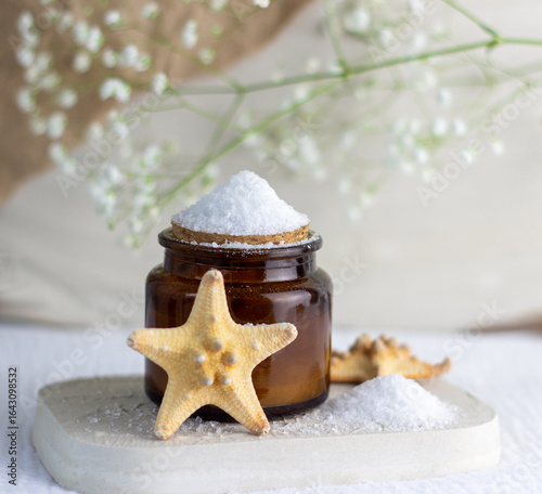 An elegant bottle in noble dark glass with natural serum and the most delicate cream to brighten your skin is decorated with an elegant flower on a plaster catwalk.