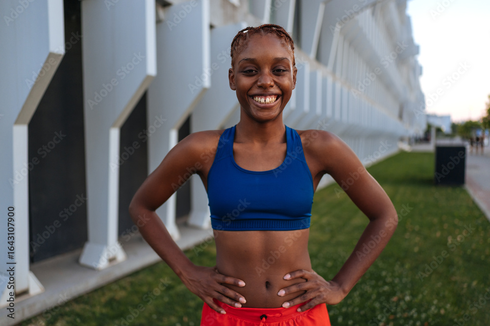 Fototapeta premium Young sporty woman smiling and posing with hands on hips