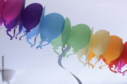 Colorful paper balloons hanging from the ceiling for a festive celebration in a bright room