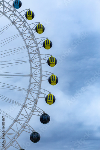 Ferris wheel on cloudy sky background, closeup of photo.