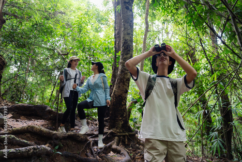 Canvas-taulu Hikers exploring tropical forest while birdwatching with binoculars