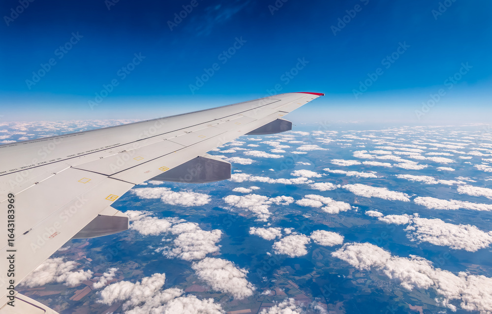 Fototapeta premium View from the airplane window at a beautiful cloudy sky and the airplane wing