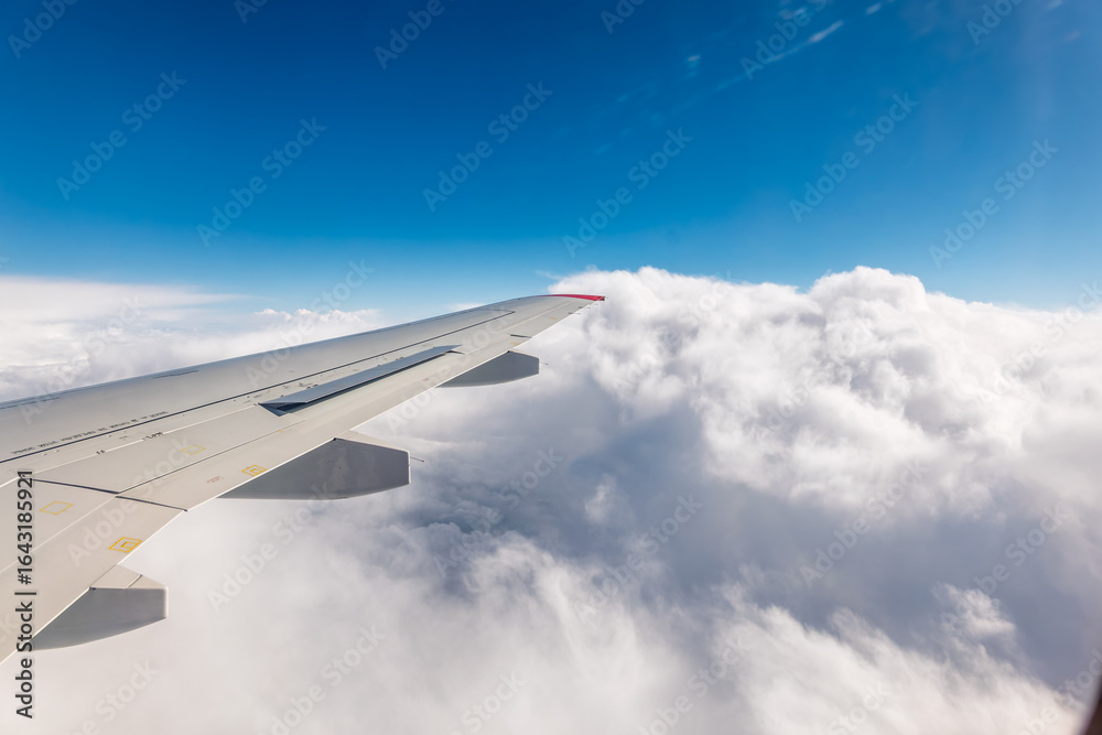 Fototapeta premium View from the airplane window at a beautiful cloudy sky and the airplane wing