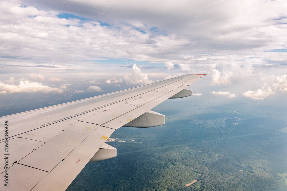 Fototapeta premium View from the airplane window at a beautiful cloudy sky and the airplane wing