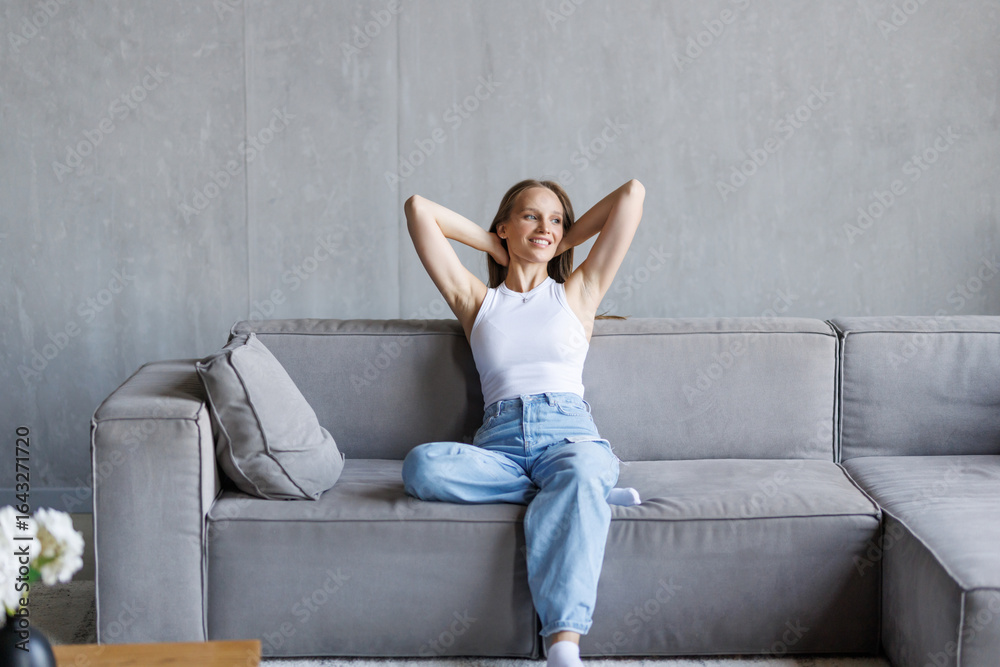 Obraz premium Young woman relaxing and sitting on a sofa at home in the morning