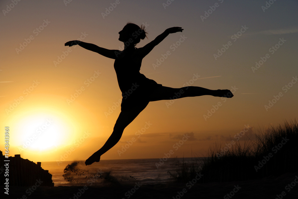 Fototapeta premium Silhouette of Woman Dancing on Beach Against Colorful Sunset Sky, Summer Concept